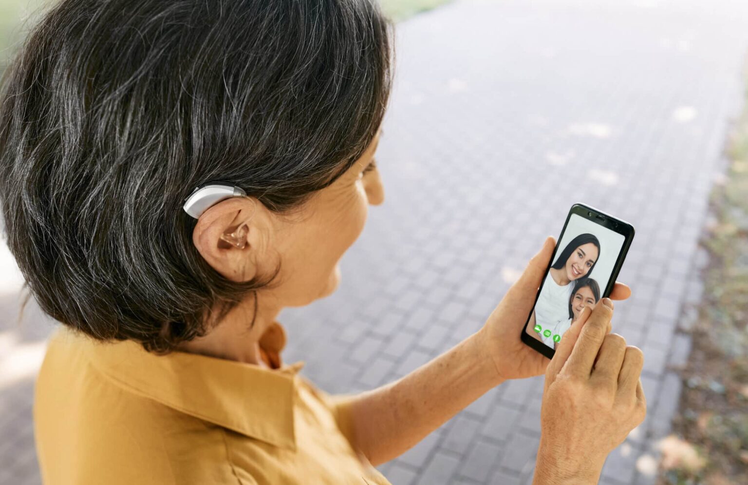 Woman with a hearing aid FaceTiming with family on her smartphone.