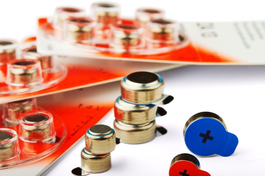 Different sizes of hearing aid battery in and out of packaging