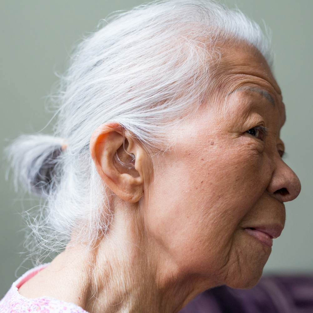 a woman wearing hearing aids shows her ear