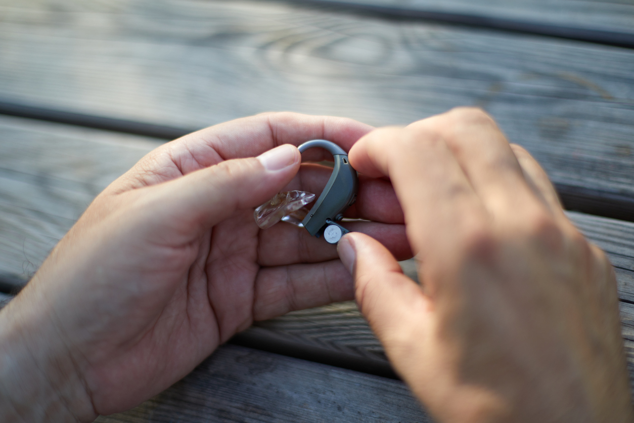 Close up of a person holding a hearing aid at a table