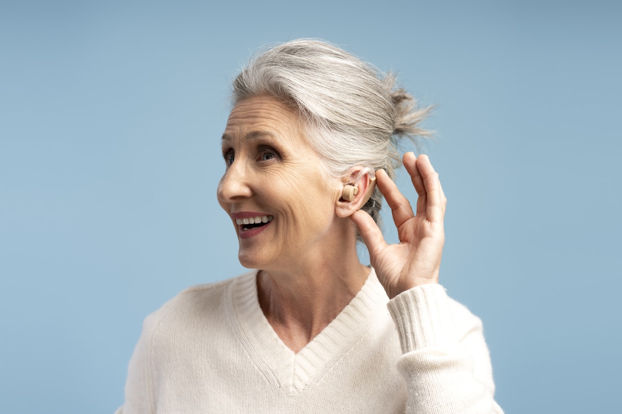 Happy senior woman showing off her hearing aid