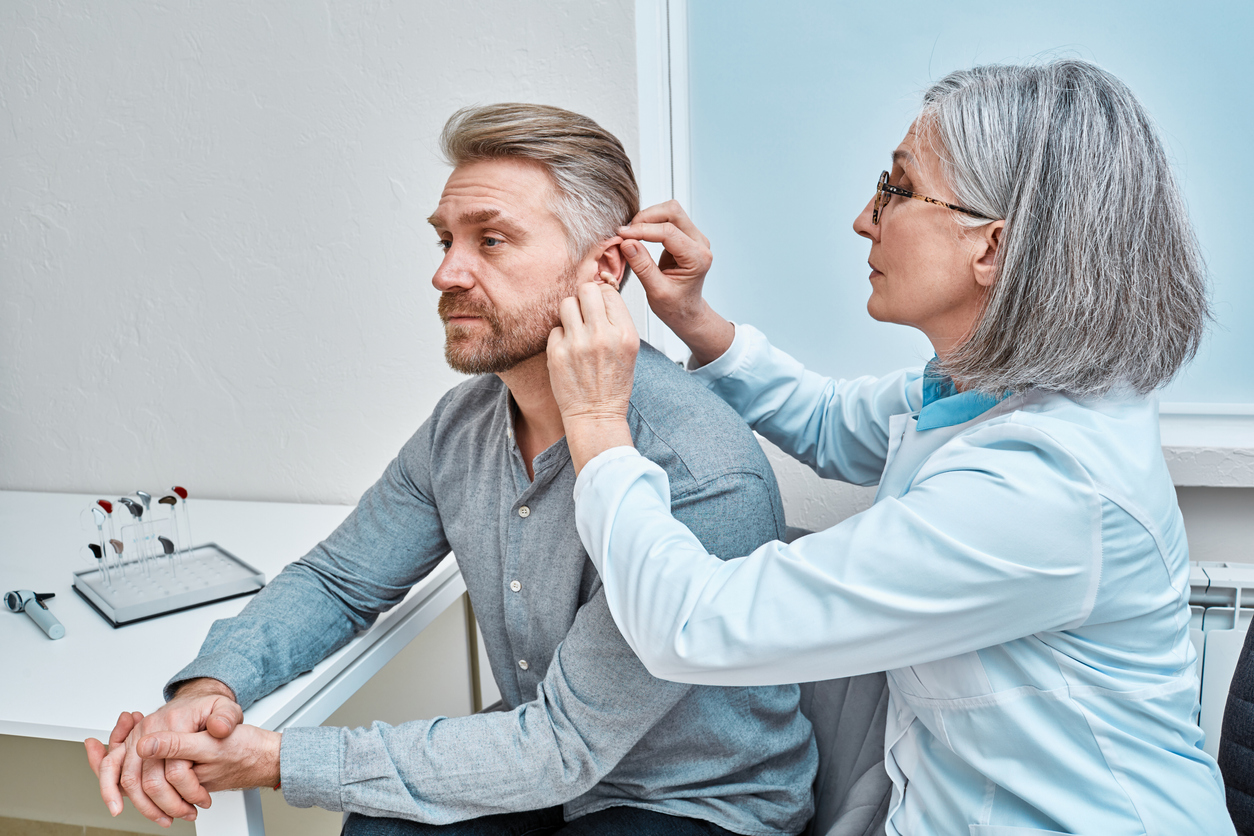 Audiologist fits her patient with a new hearing aid.