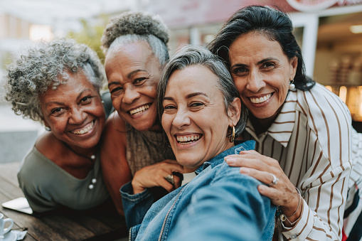 Group of smiling friends at an outdoor cafe.