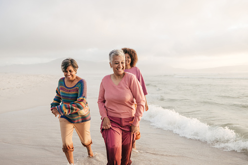 Group of confident elderly friends playing in the water on a beach.