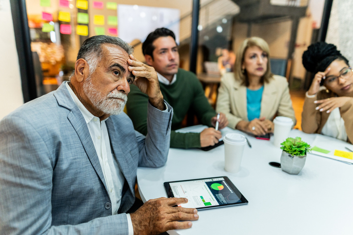 Colleagues at work around a table listening to speech
